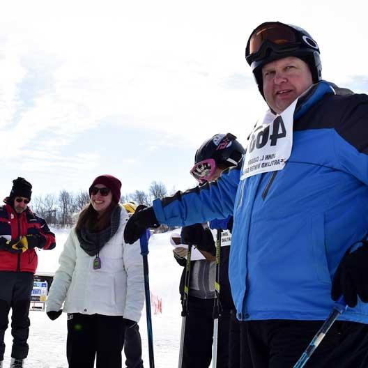 一位穿着滑雪装备的特奥会运动员，旁边是一位九游会的学生志愿者